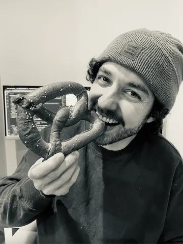 Stefan Stahuber, founder of WebPretzel, biting into a pretzel at his desk